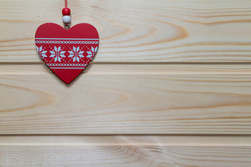 Wooden red heart suspended on a natural wood background.Valentin