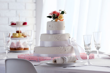 Wedding layered cake on decorated table in restaurant