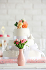 Wedding cake and flowers in vase on decorated table
