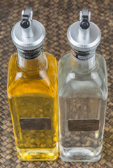 Vegetable cooking oil and white vinegar in a glass bottles over wicker background