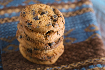 Cookies with chocolate crumbs on ornament napkin against blurred background, close up