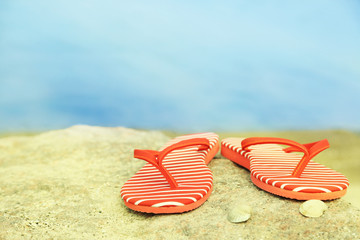 Bright flip-flops on stone, nature background