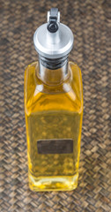 Vegetable cooking oil in an oil dispenser bottle over wicker background