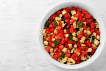 Ratatouille, stewed vegetable dish with tomatoes, zucchini, eggplant before cooking, on wooden background