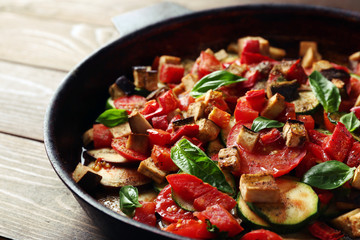 Tasty vegetarian ratatouille made of eggplants, squash, tomatoes and onions in black cast iron pan,...