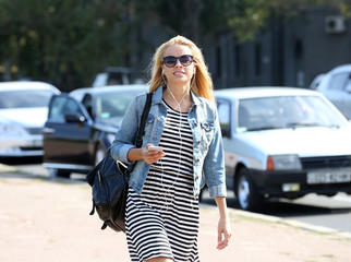 Young woman listening to music and walking along the street