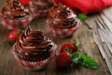 Chocolate cupcakes and strawberries on wooden background