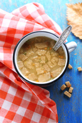 Mug of soup and napkin on blue wooden background