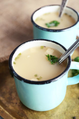 Mugs of soup on metal tray on a table