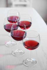 Glasses of red wine on table on bright background