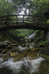 Beautiful water flow with concrete bridge with wood look. waterfall and green forest