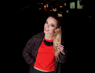 Beautiful stylish young woman walking on the street at night