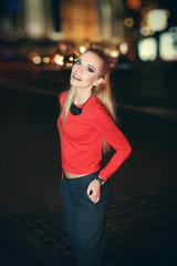 Beautiful stylish young woman walking on the street at night