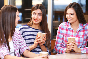 Three smiling friends speaking with coffee in hands