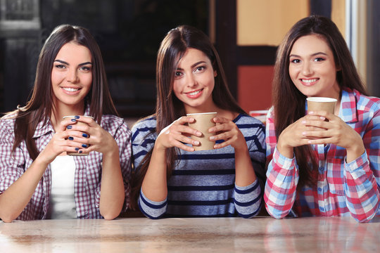 Portrait of three smiling friends sitting in cafe with coffee
