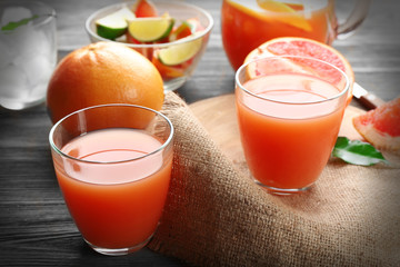 Citrus juice with ice and fresh fruits on cutting board