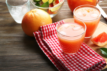 Citrus juice with ice and fresh fruits on cutting board