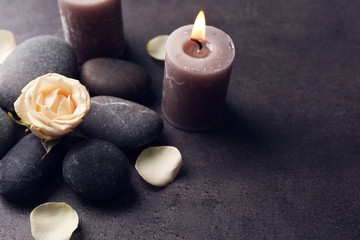 Obraz na płótnie Canvas Relax concept - composition of aroma candles with pebbles and flower on grey background
