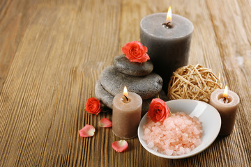 Fototapeta na wymiar Relax set which include aroma candles, flowers, petals and pebbles on wooden background