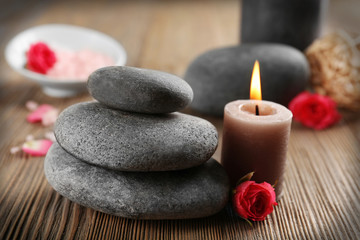 Relax set which include aroma candles, flowers, petals and pebbles on wooden background