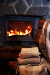 Knitted clothes on chair on fireplace background