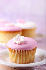 Tasty cupcake on saucer, on light background