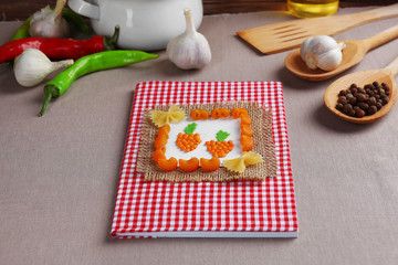 Recipe book and ingredients for cooking on a table in kitchen