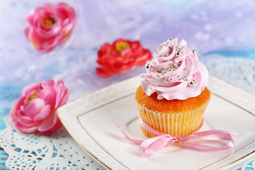 Tasty cupcake on plate, on light background