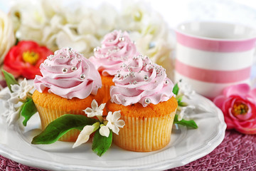 Tasty cupcakes on plate, on light background