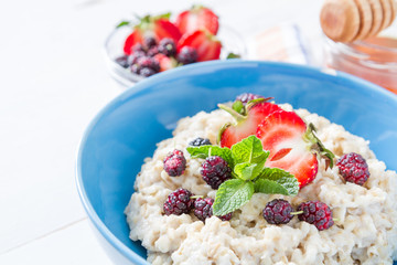 Breakfast - oatmeal with honey and berries, blue bowl