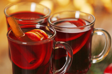 Mulled wine with spices and Christmas tree on wooden background