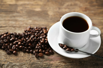 Cup of coffee and coffee grains on wooden background