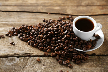 Cup of coffee and coffee grains on wooden background