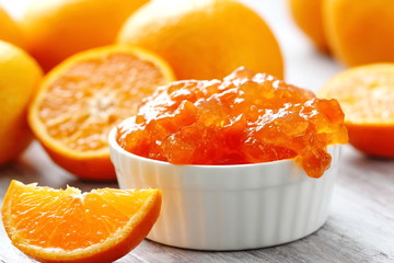 Tangerine jam in white bowl with fresh fruit