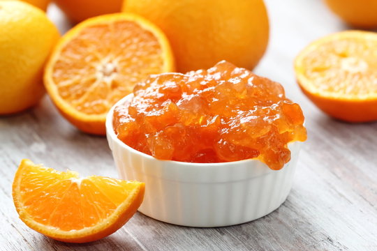 Tangerine jam in white bowl with fresh fruit