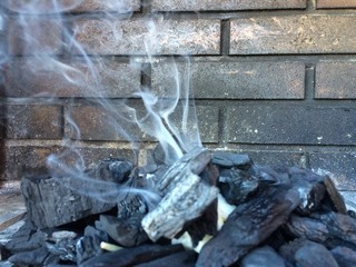 Coal, bricks and smoke. Starting a barbecue fire.