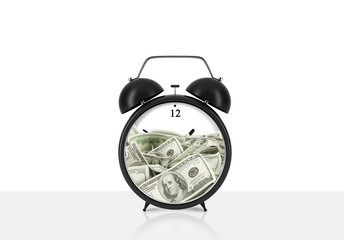 An alarm clock with dollar bills inside is on the table. The concept of 'time is money' and a time...