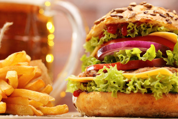 Grilled hamburger with fries and beer on brick wall background