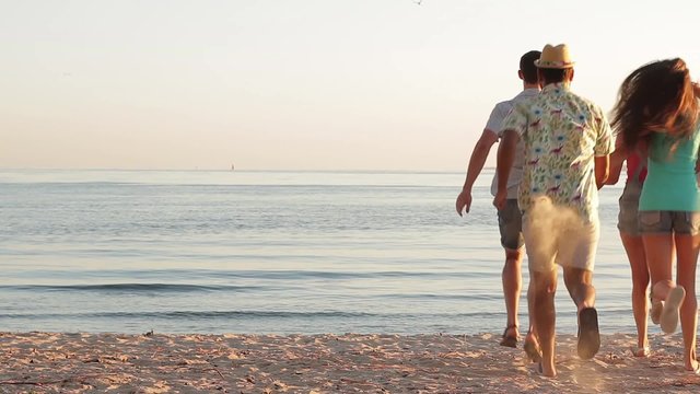 Guys and girls running on the wild beach.