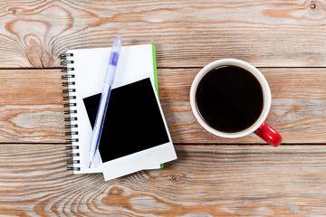Workspace with coffee cup, instant photos, note paper and notebo
