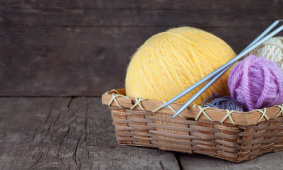 Balls of yarn in basket with knitting needles