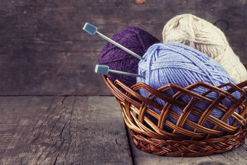 Skeins colored yarn and knitting needles in a basket