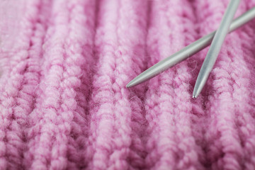 Two knitting spokes and pink knitted swatch