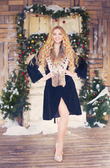 Fototapeta na wymiar Beautiful happy woman in furcoat by the Christmas decorations