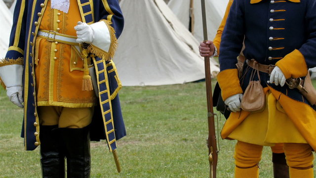 Two guards in yellow and blue coat uniform. They are standing and holding their guns while waiting