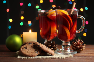 Cup with mulled wine and lemon slices and cinnamon with anise lying next to the bowl of honey on wooden table, on lights background