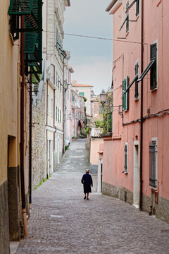 A old woman walking alone in a narrow street