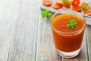 Fresh carrot juice in glass on wooden table, healthy vegetable drink