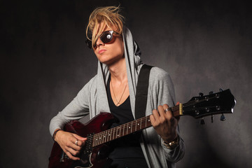 Obraz premium blond young man with messy hair playing guitar in studio