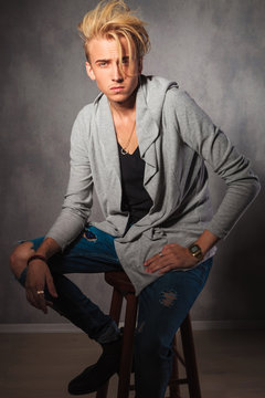 Serious Male Model Wearing Rugged Jeans And Sitting On A Chair I